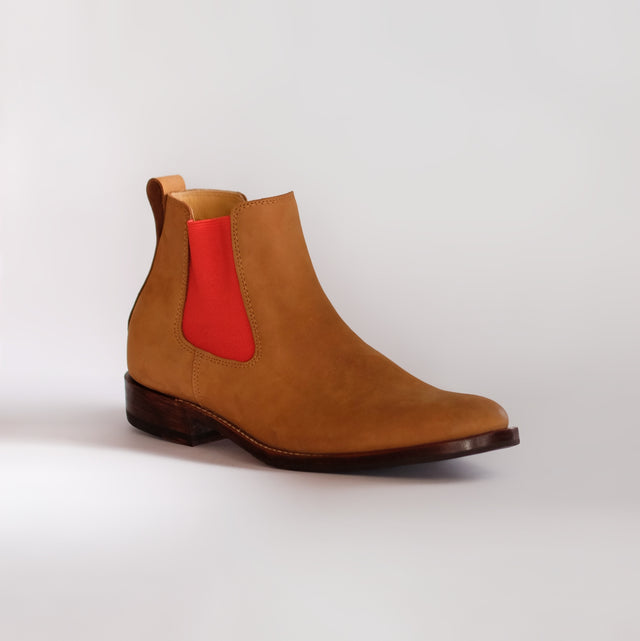 Brown Chelsea boot with a red elastic on a white background
