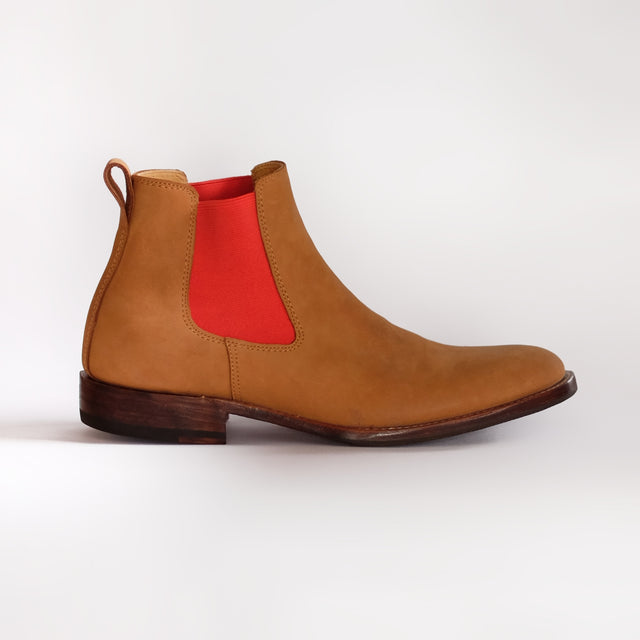 Tan Chelsea boot with a red patch on a white background