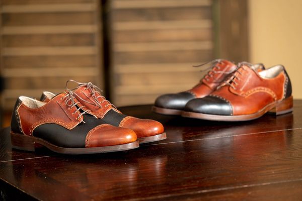 2 pairs of custom Derby shoes on a wooden table